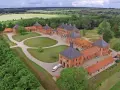 Luftaufnahme von Schloss Bothmer, einem barocken Anwesen mit roten Ziegelgebäuden, umgeben von grünen Gärten und Feldern.