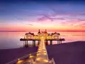 Pier mit beleuchtetem Gebäude im Abendrot, ein romantischer Blick auf die Sellin Innenstadt.