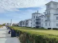 Weiße Villen säumen die Heiligendamm Promenade. Menschen spazieren und genießen die Aussicht auf das Meer.