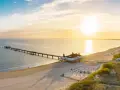 Sonnenuntergang am Ostsee Strand mit langer Seebrücke und Strandkörben.