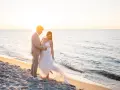 Ein glückliches Brautpaar feiert seine Hochzeit am Strand. Die Sonne geht unter und taucht die Szene in warmes Licht.