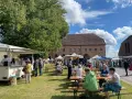 Sommerliche Zarrentin Veranstaltungen: Menschen genießen ein Fest mit Ständen und Sitzgelegenheiten im Freien vor historischen Gebäuden.