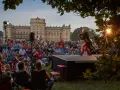 Ein Geiger spielt auf einer Bühne vor einem Schloss, während ein Publikum zusieht. Ein schönes Beispiel für Veranstaltungen an der Ostsee.