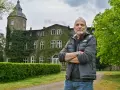 Mann vor dem historischen Gutshaus Wesselstorf, das von Efeu umrankt ist.