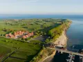 Ferienhäuser am Meer, daneben ein Golfplatz. Ein kleiner Hafen mit Booten.
