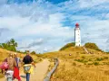Wanderweg zum Leuchtturm Dornbusch auf Hiddensee Vitte. Menschen spazieren auf einem Feldweg durch trockenes Gras.