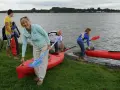 Familie bereitet sich auf einen Aktivurlaub an der Ostsee vor, holt Kajaks und Paddel aus dem Wasser.
