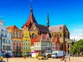 Bunte Giebelhäuser und die Marienkirche prägen das Bild der Rostocker Innenstadt. Ein sonniger Tag auf dem Platz.