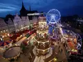 Ein beleuchteter Weihnachtsmarkt Mecklenburgische Seenplatte mit Riesenrad, Pyramide und Buden.