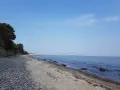 Ein ruhiger Tag am Wittenbeck Strand. Kies und Sand treffen auf das sanfte Meer, im Hintergrund eine Marina.