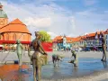 Bronzefiguren am Brunnen in Ribnitz-Damgarten, mit Kirche und Fachwerkhäusern im Hintergrund. Ein Ort, der an Bernstein erinnert.