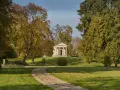 Herbstlicher Spaziergang im Schlossgarten Neustrelitz. Ein Weg führt zu einem antiken Mausoleum, umgeben von bunten Bäumen.