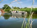 Familie genießt eine Fahrt mit einem Auto-Boot von Kiki's Bootsverleih auf einem ruhigen See, umgeben von üppigem Grün.