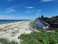 Ein reetgedecktes Haus am Strand von Ahrenshoop, mit Blick auf die Ostsee und den Sandstrand.