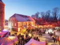 Belebter weihnachtsmarkt plau am see vor historischer Kulisse mit beleuchteten Buden und vielen Besuchern.