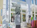 Schild an der Kunstmeile Binz: Keramik, Schmuck, Porzellan, Glas, Textil, Malerei, Fotografie, Bar & Café. Bunte Schals hängen davor.