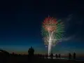 Silhouetten von Menschen am Strand beobachten ein beeindruckendes Feuerwerk über dem Meer. Ein leuchtendes Spektakel in Rot und Grün erhellt den Nachthimmel. Feuerwerk Usedom.