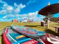 Windsurfausrüstung liegt am ummanz strand. Im Hintergrund bunte Segel und Menschen, die sich auf das Wasser vorbereiten.