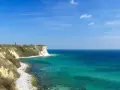 Türkisblaues Meer und Kreidefelsen am Kap Arkona. Ein Leuchtturm wacht über die Küste.
