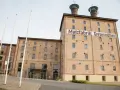 Die imposante Malzfabrik Grevesmühlen, ein Backsteingebäude mit markanten Türmen, steht im hellen Tageslicht.