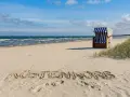 Der Juliusruh Strand lädt mit einer Strandmuschel und dem Schriftzug "KUSTENKORS" im Sand zum Verweilen ein.