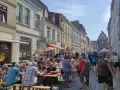 Menschen genießen ein Fest vor dem Kulturhaus Teterow. Viele sitzen an Tischen, essen und unterhalten sich.
