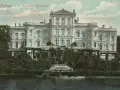 Das Schloss Putbus, von der Rückseite betrachtet, thront majestätisch über einem üppigen Garten und einem ruhigen Gewässer.