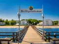 Holzsteg führt zum Heiligendamm Strand mit weißen Gebäuden und blauem Himmel.