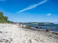 Kinder spielen am lobbe strand. Sand, Steine und das Meer bilden eine idyllische Szene unter blauem Himmel.