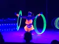 Artistin dreht leuchtende Reifen auf der Bühne des Circus Moreno. Neonfarben und Schwarzlicht erzeugen eine magische Atmosphäre.