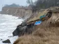 Ein alter Bunker am Strand, von der Erosion freigelegt und mit Graffiti bemalt, trotzt den Wellen.