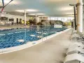 Ein großes Schwimmbecken mit blauen Kacheln und einer Felswand lädt zum Badespaß ein. Hier ist das perfekte Erlebnisbad Ostsee für die ganze Familie.