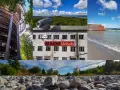 Ein Aussichtsturm, das Dokumentationszentrum Prora mit der Aufschrift "Macht Urlaub", ein Graffiti-bedeckter Mauerrest am Meer und ein steiniger Strand.