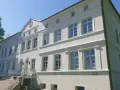 Das Herrenhaus Blengow, ein weißes Gebäude mit vielen Fenstern, steht unter blauem Himmel.