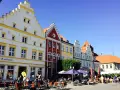 Bunte Häuserfronten säumen den mv markt. Menschen sitzen in Cafés unter Sonnenschirmen und genießen den sonnigen Tag.