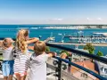 Drei Kinder blicken auf einen belebten Hafen mit vielen Segelbooten. Ein schöner Tag für Veranstaltungen MV mit Kindern.