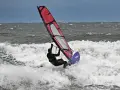 Windsurferin in Aktion auf der Ostsee, die mit ihrem Segel über die Wellen springt.
