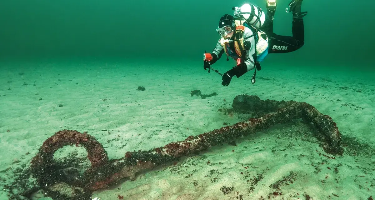 Taucher erkundet ein altes Ankerwrack in der Ostsee.