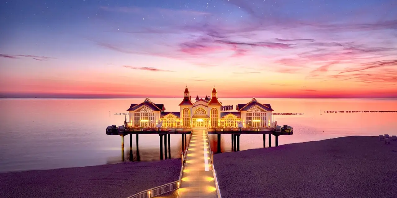 Pier mit beleuchtetem Gebäude im Abendrot, ein romantischer Blick auf die Sellin Innenstadt.