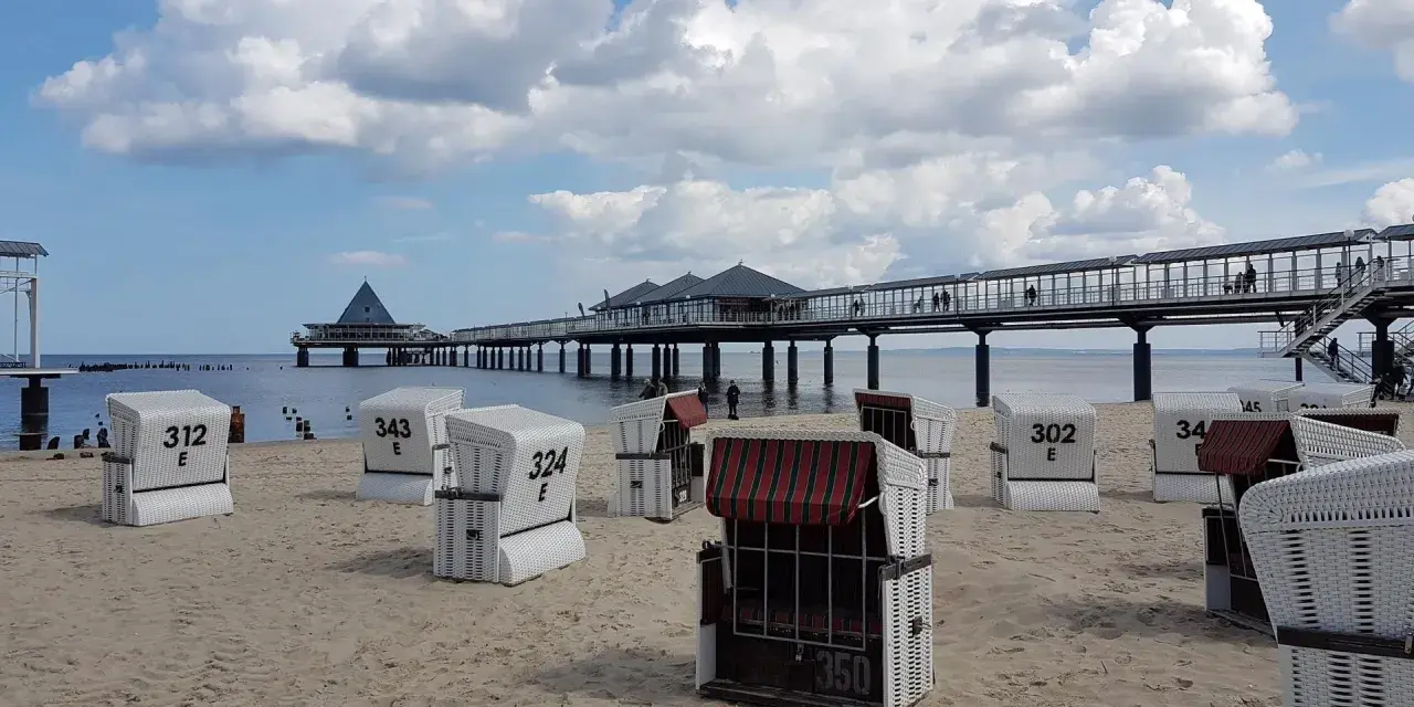 Strandkörbe am Zirchow Strand, mit Seebrücke und Wolkenhimmel.