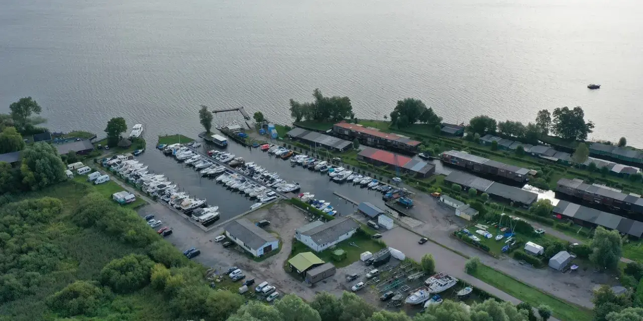 Luftaufnahme des Hafens Plau am See mit vielen Booten, Wohnmobilen und Gebäuden. Ein lebendiges Hafenfest-Flair liegt in der Luft.