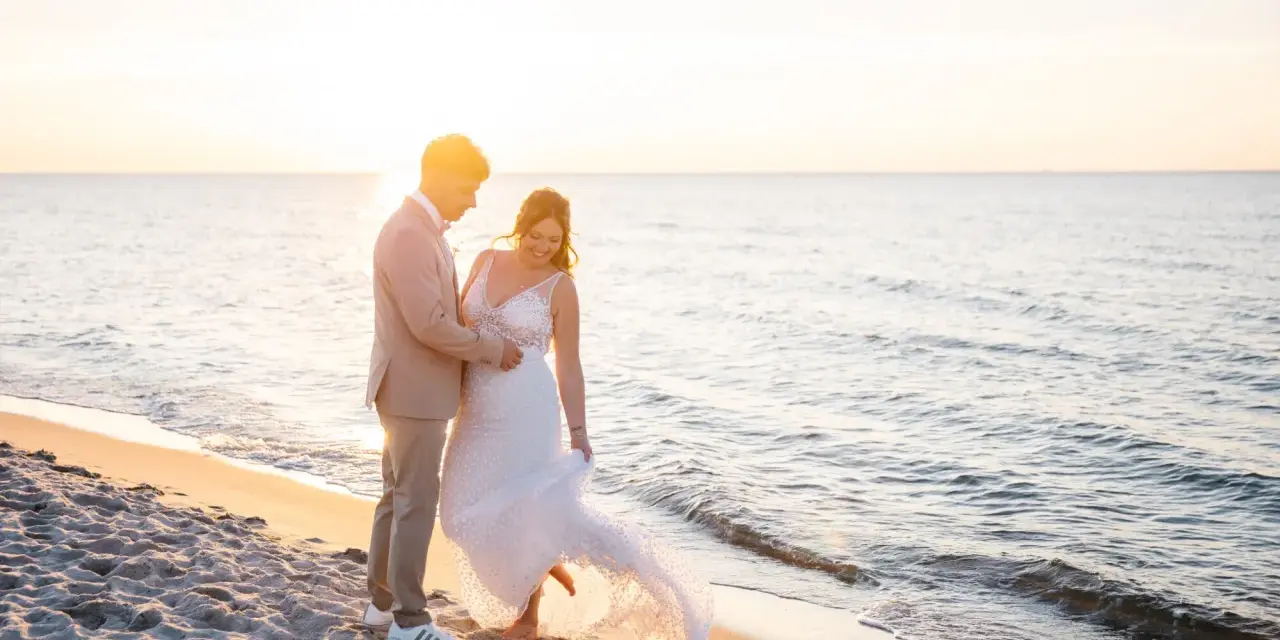 Ein glückliches Brautpaar feiert seine Hochzeit am Strand. Die Sonne geht unter und taucht die Szene in warmes Licht.