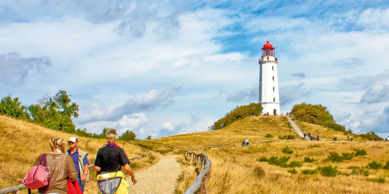 Wanderweg zum Leuchtturm Dornbusch auf Hiddensee Vitte. Menschen spazieren auf einem Feldweg durch trockenes Gras.