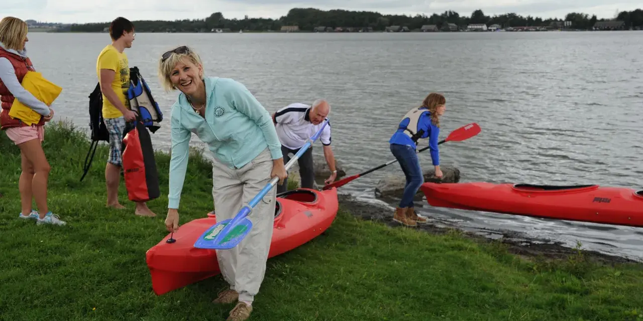Familie bereitet sich auf einen Aktivurlaub an der Ostsee vor, holt Kajaks und Paddel aus dem Wasser.