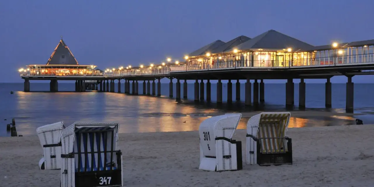 Strandkörbe am Abend vor der beleuchteten Seebrücke in Heringsdorf. Ein perfekter Ort für Geheimtipps am Meer.