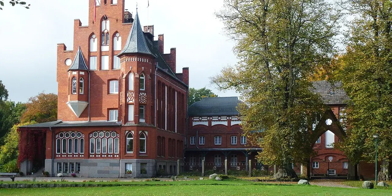 Das imposante Schloss Kalkhorst, ein Backsteinbau mit Türmchen und Erkern, steht im Herbstlicht.