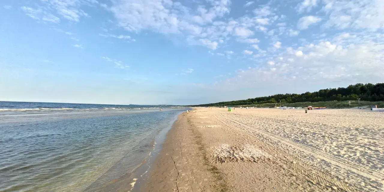 Sonniger Karlshagen Strand mit sanften Wellen und weitem Sand. Ein perfekter Ort für entspannte Tage am Meer.