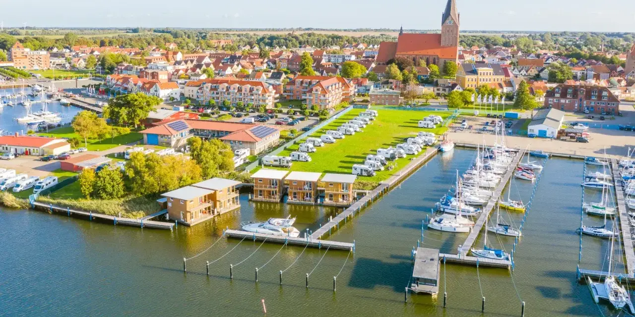 Blick auf Barth an der Ostsee mit Yachthafen, Wohnmobilstellplätzen und modernen Ferienhäusern am Wasser.