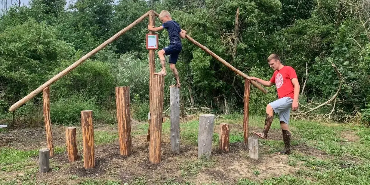 Junge und Mann balancieren auf Baumstämmen im Kletterpark Plau am See.
