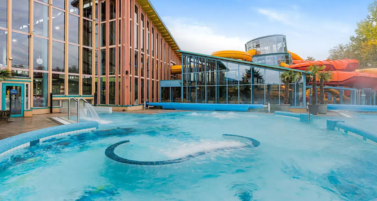 Einladende Therme an der Ostsee mit großem Pool und bunten Wasserrutschen im Hintergrund.